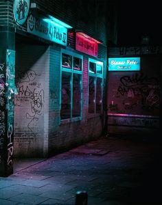 a building that has some graffiti on the side of it at night with neon lights