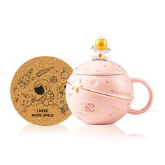 a pink teapot shaped like an egg next to a cookie jar with space related designs on it