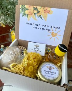 a box filled with honey, soap and flowers next to a sign that says sending you some sunshine shines