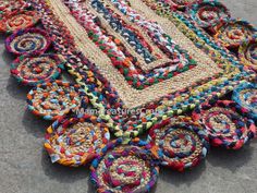 a multicolored rug is laying on the ground next to some rolls of yarn