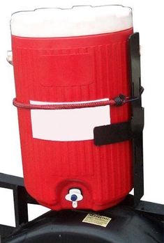 a red cooler sitting on top of a black wheel