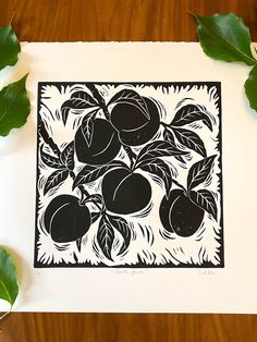 a black and white linoleum print with fruit on it, surrounded by green leaves