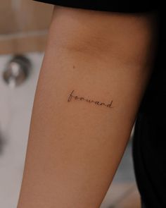 a woman's arm with the word forward tattooed on her left side ribcage