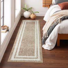 a bed room with a neatly made bed and a large rug on the wooden floor