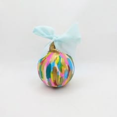 an ornament with a blue bow on it's top and multicolored paint