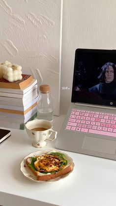 an open laptop computer sitting on top of a desk next to a plate with food