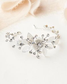 a bridal bracelet with crystal flowers and leaves on the side, sitting next to a rose