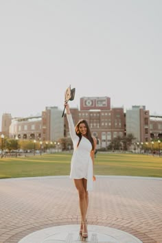 a woman in a white dress is holding up a fan and posing for the camera