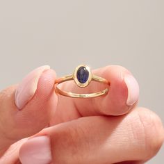 The 14k Solid Gold Oval Blue Ring showcases a captivating bluish-purple iolite gemstone, perfect for an engagement or special celebration. This bezel-set birthstone solitaire ring is a beautiful, handmade piece of jewelry designed for women. Crafted in 14k solid gold, it adds a touch of elegance and uniqueness to her collection. Ring Details   ❥ Gold KT: 14k Solid Gold (also in 10, 18K)  ❥ Gold Color Options: White, Yellow, Rose Gold  ❥ Top Width: 8.00x6.20 mm  ❥ Top Thickness: 4.65 mm  ❥ Band W Modern Oval Cabochon Sapphire Ring, Modern Sapphire Ring With Oval Cabochon, Modern Oval Tanzanite Sapphire Ring, Tanzanite Oval Birthstone Promise Ring, Oval Tanzanite Birthstone Promise Ring, Oval Tanzanite Birthstone Ring, Modern Cabochon Sapphire Ring For Gift, Fine Jewelry 14k Gold Sapphire Ring With Oval Cabochon, Sapphire Bezel-set Oval Cabochon Ring