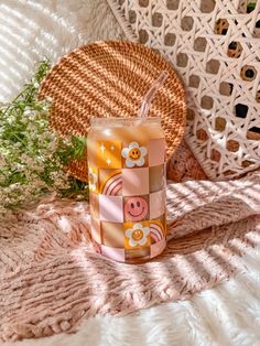 an orange and pink candle sitting on top of a white blanket next to a wicker basket