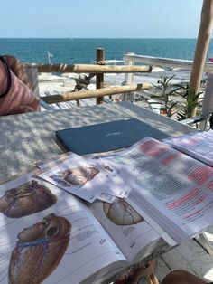 an open book sitting on top of a wooden table next to the ocean and beach