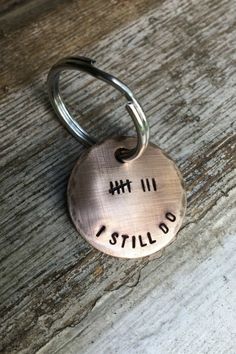 a metal keychain with the words i still do on it sitting on a wooden surface