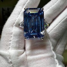 Carbon created 28CT emerald cut Swiss blue topaz statement ring.  This carbon created aquamarine has a 20% higher refractive index and 16.6% more gloss than earth mined diamonds.  🔥Looking for spectacular fire?  925 sterling silver/ 18K white gold plating 28CT carbon based aquamarine 2 x 1CT trillion cut carbon based accents stones Size  7 for immediate shipping Luxury Blue Cubic Zirconia Topaz Ring, Luxury Blue Topaz Diamond Cut Jewelry, Luxury Exquisite Topaz Wedding Ring, Luxury Brilliant Cut Topaz Ring In Fine Jewelry Style, Luxury Dazzling Blue Topaz Rings, Luxury Topaz Birthstone Gemstones, Blue Gia Certified Emerald Ring For Formal Occasions, Blue Radiant-cut Emerald Ring In Fine Jewelry Style, Blue Radiant Cut Emerald Ring In Fine Jewelry