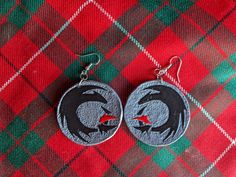 pair of earrings with black and red bird on plaid fabric, sitting on top of each other