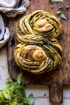 a wooden cutting board topped with rolls covered in pesto