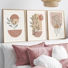 three framed art prints hanging on the wall above a bed with pink pillows and blankets