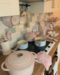 pots and pans are sitting on the stove top in this kitchen with pink accents