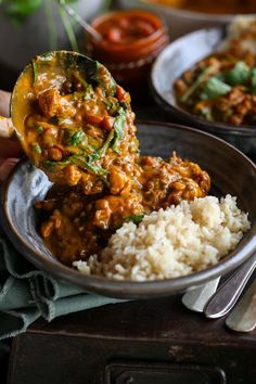 a bowl filled with rice and meat covered in sauce