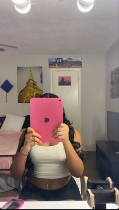 a woman sitting in front of a pink ipad holding it up to her face with both hands