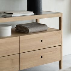 a wooden dresser with two drawers and a towel on the top shelf next to it