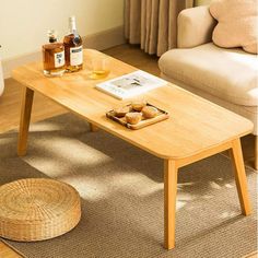 a coffee table with some drinks on it in front of a couch and window sill