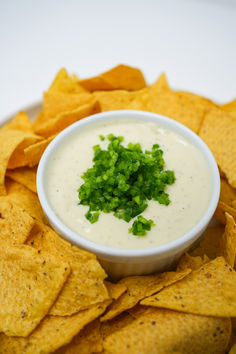 a white bowl filled with guacamole surrounded by tortilla chips