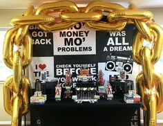 a table topped with gold balloons and lots of money on it's back wall