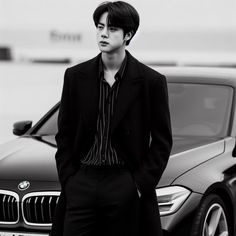 a young man standing next to a car