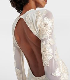 the back of a woman's dress with white flowers on it and sheer sleeves