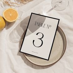 a table number on a plate next to some oranges