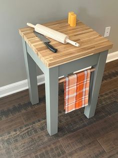 a wooden table with a knife and towel on it next to a gray painted wall