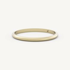 a thin yellow gold wedding band with a small diamond in the center, on a white background