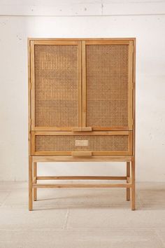 a wooden cabinet with wicker doors and drawers on the bottom, against a white wall