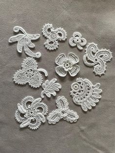 white lace appliques are laid out on a gray surface, including one in the middle