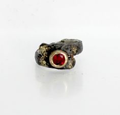 I set a 6mm round faceted ruby in a 14k gold setting. Around the setting I fused 18k gold for interest and contrast. Ruby is the birthstone for July. Casual  or formal wear ring. The band is sterling silver with a fused texture. A black patina was used to make the various elements stand out. Over time the patina will wear off the high points leaving a pleasing two tone effect. The band averages 11mm at the top and 5mm wide by 2mm thick. I designed and made this ring. You can order this ring in any size. Free shipping in the USA. Hand Forged Ruby Ring Jewelry, Hand Forged Ruby Ring, Hand Forged Ruby Ring For Anniversary, Anniversary Ruby Rings Hand Forged, Anniversary Hand Forged Ruby Rings, Hand Forged Ruby Ring In Red, Hand Forged Red Ruby Ring, Unique Hand Forged Ruby Ring For Anniversary, Hand Forged Round Ruby Rings