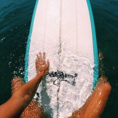 two people on a surfboard in the water with their feet propped up against the board