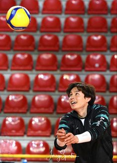 a young man playing volleyball in front of an empty stadium bleachers with red seats