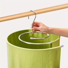 a person is holding a metal object over a green trash can with a wooden stick sticking out of it