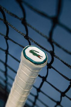 a white and green tennis racquet sitting on top of a net next to a blue sky