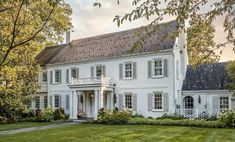 a large white house sitting on top of a lush green field