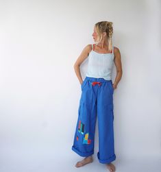 Ultra-flattering high waist cargo pants with drawstring waist from the 90s era. Slightly flared with foldover waistband. Graphic details on front & back that make them special. Very comfortable. In excellent condition. Measurements are taken flat. Fit actual M Waist = 13.5" in (un-stretched) / 34 cm (un-stretched) Hip = 19.5 in / 50 cm Rise = 12.5 in / 32 cm Inseam = 29 in / 73 cm Total length = 40 in / 102 cm Model is 5'6", 26" waist, 36" hip and wears a modern 2-4 Fit guide: It's always a good Retro Wide Leg Cargo Jeans For Spring, Retro Spring Pants With Cargo Pockets, Retro Pants With Cargo Pockets For Spring, Retro Cargo Pants For Spring, Retro Cargo Pocket Bottoms For Spring, Blue Cotton Cargo Jeans For Summer, Retro Straight Leg Spring Cargo Pants, Retro Wide Leg Cargo Pants For Spring, 90s Style Summer Cotton Cargo Jeans