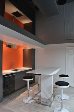 an empty kitchen with three stools in front of the counter and bar area next to it