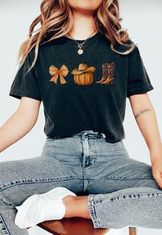 Say "Howdy" to autumn in style with our Howdy Pumpkin Coquette Comfort Colors Shirt. This charming tee blends western flair with cozy fall vibes, making it perfect for both Halloween and Thanksgiving celebrations. Featuring a cute pumpkin design with a coquette twist, this shirt is ideal for cowgirls who love to embrace the season with a touch of country charm. Whether you're out on the ranch or enjoying a fall festival, this Western-inspired tee, complete with a playful fall bow, is the perfect Cute Short Sleeve Tops For Fall, Cute Fall Crew Neck Shirt, Cute Crew Neck Fall Shirt, Cute Crew Neck Shirt For Fall, Cute Short Sleeve Fall Shirt, Cute Short Sleeve Shirt For Fall, Cute Cotton Shirt For Fall, Howdy Pumpkin, Fall Bows