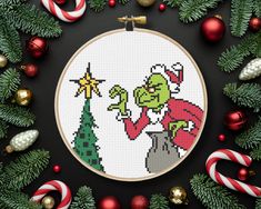 a cross stitch christmas scene with candy canes and ornaments around the hoop on a black background