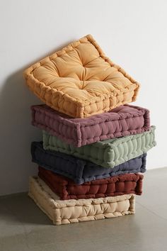 a stack of pillows sitting on top of each other in front of a white wall