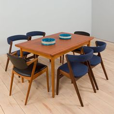 a wooden table with six chairs around it on a hard wood floored area next to a white wall