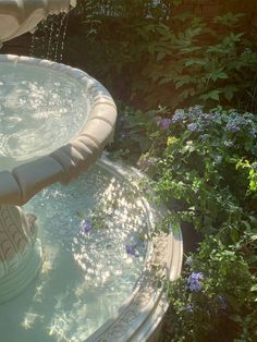 a water fountain surrounded by flowers and greenery