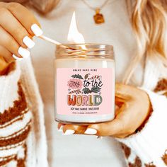 a woman is holding a candle that says, do it to the world