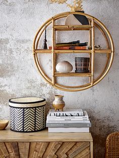 a round shelf with books and vases on it next to a wicker basket