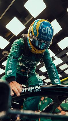 a man in a racing suit and helmet sitting on top of a car